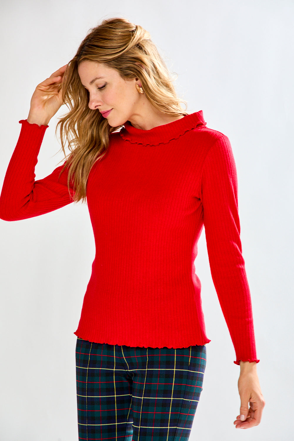 Woman wearing a red sweater and plaid pants on a white background