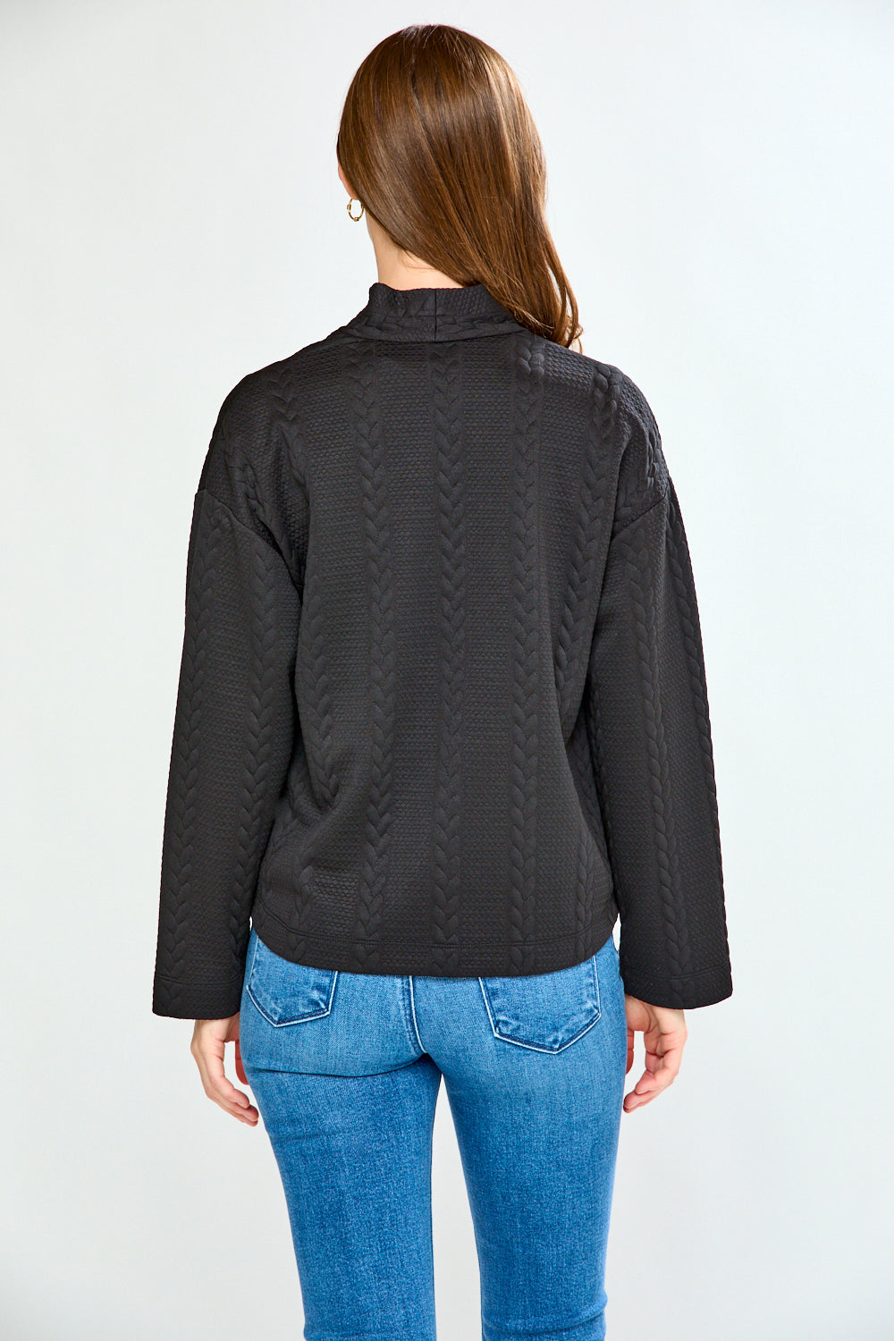 Woman wearing a black jacket and blue jeans on a white background