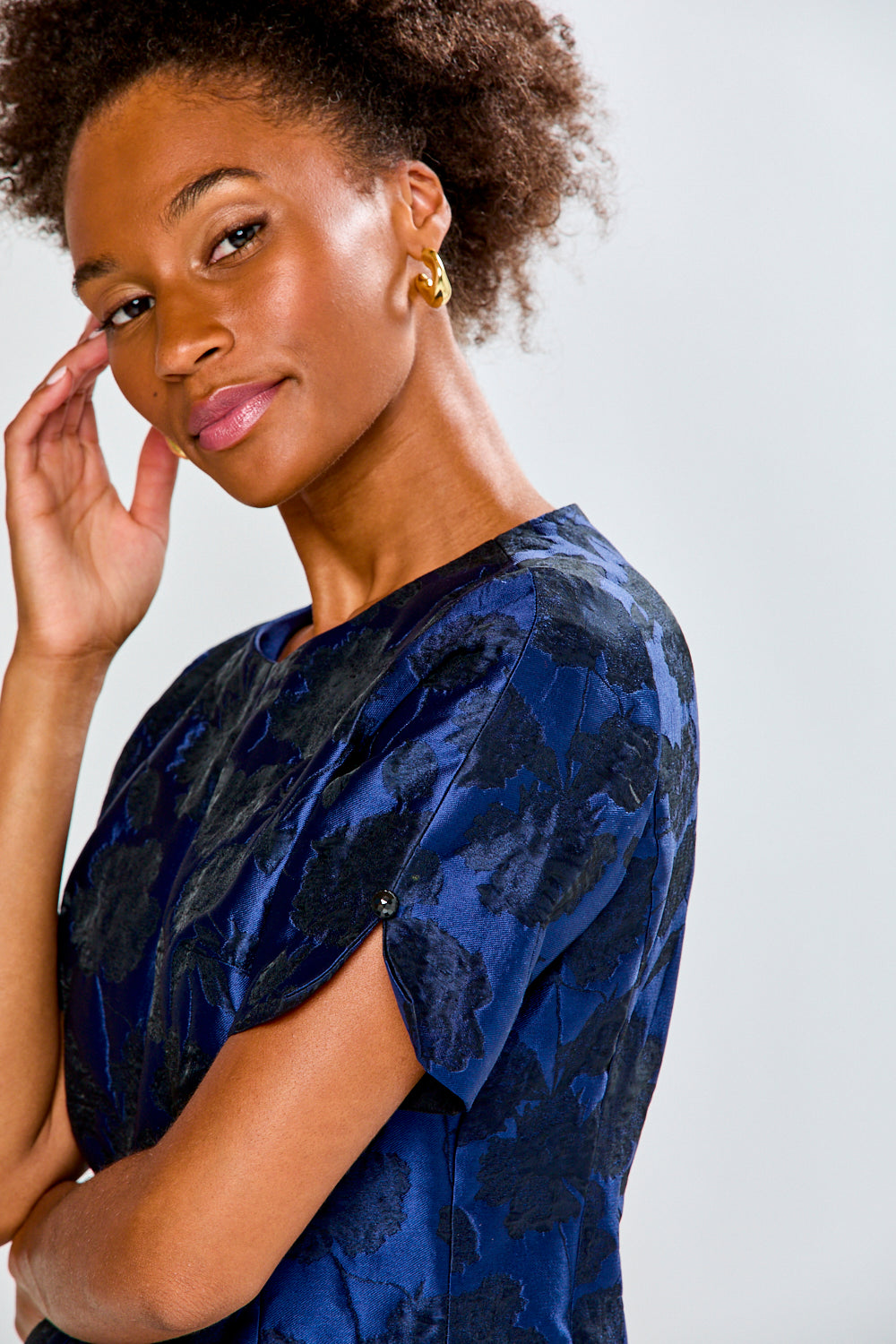 Woman wearing a blue patterned dress against a plain background