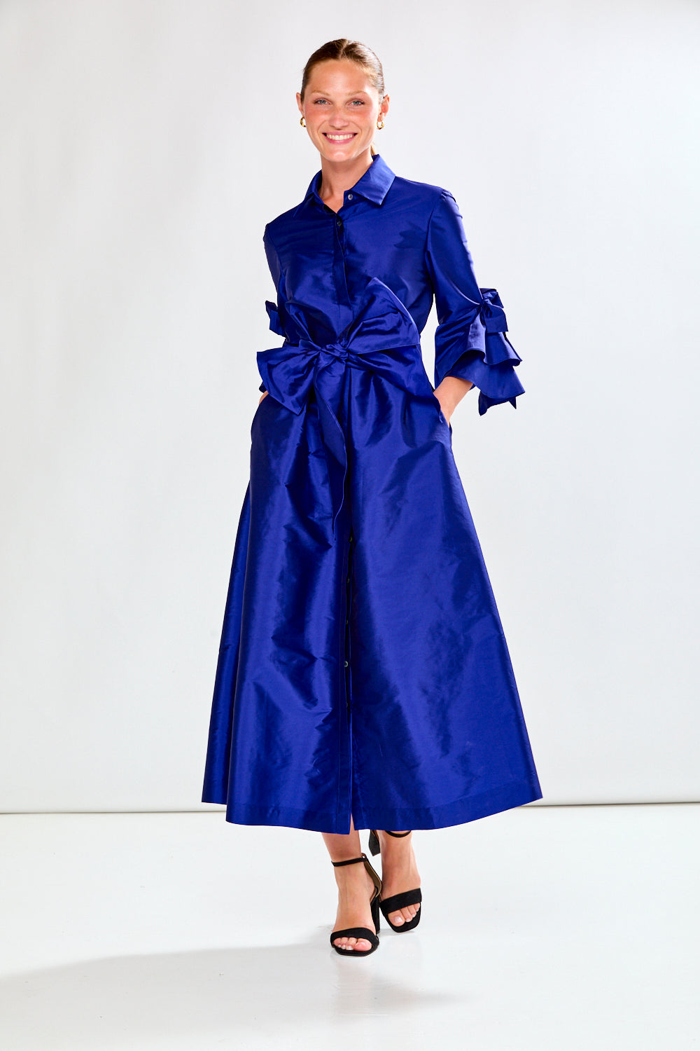 Woman wearing a blue dress with a large bow on a white background