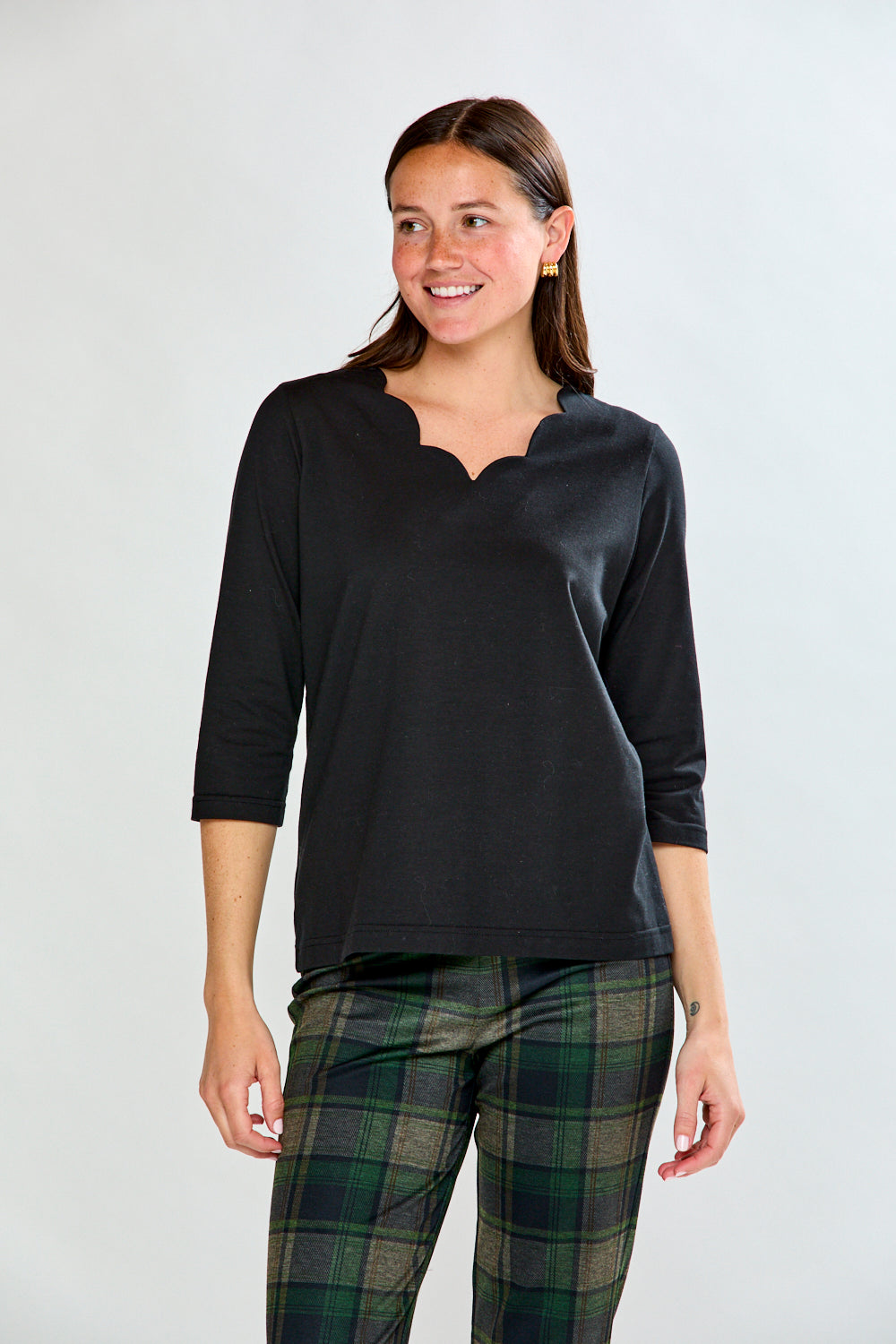 Woman wearing a black top and plaid pants on a white background