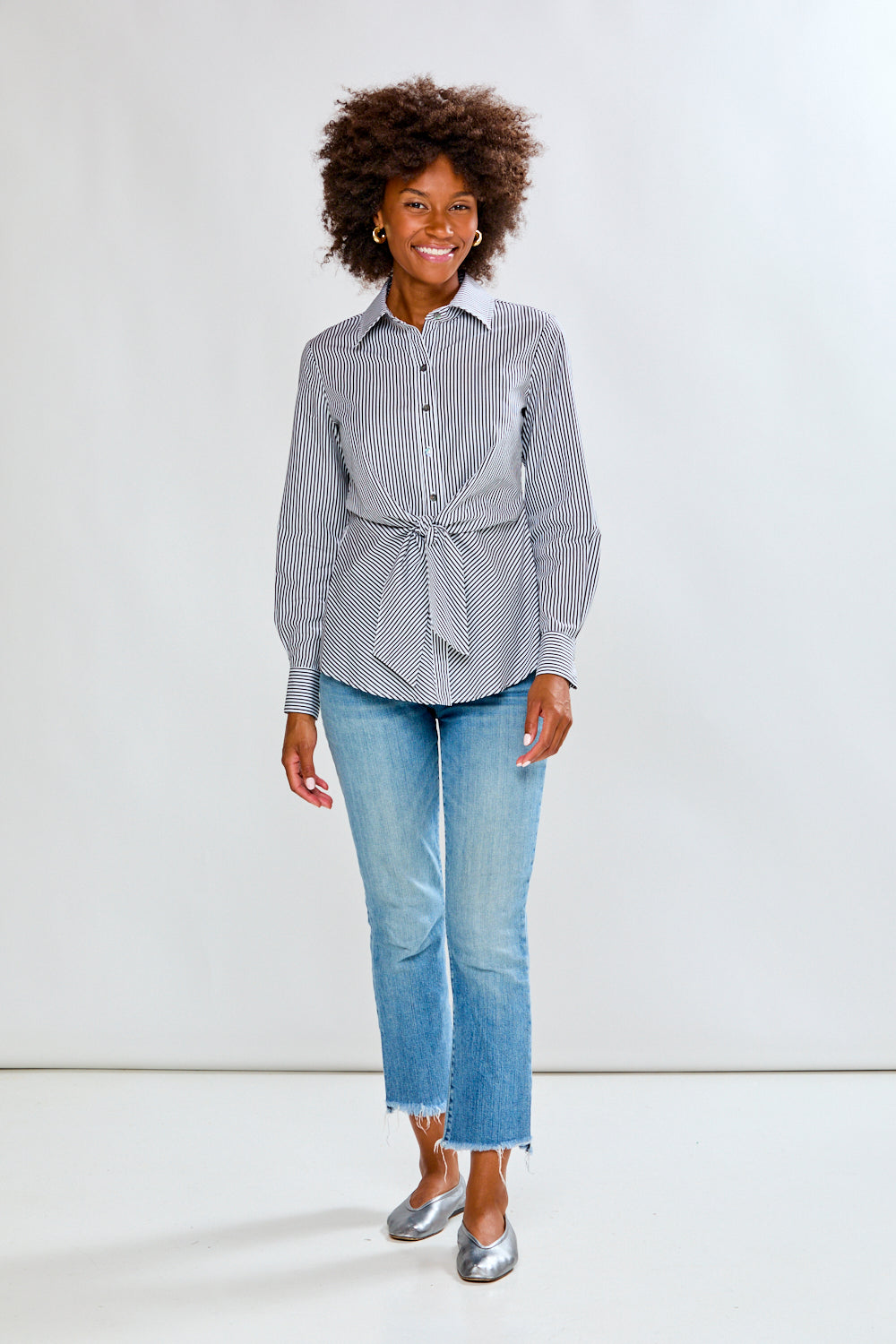 Woman wearing a striped shirt and jeans on a plain background
