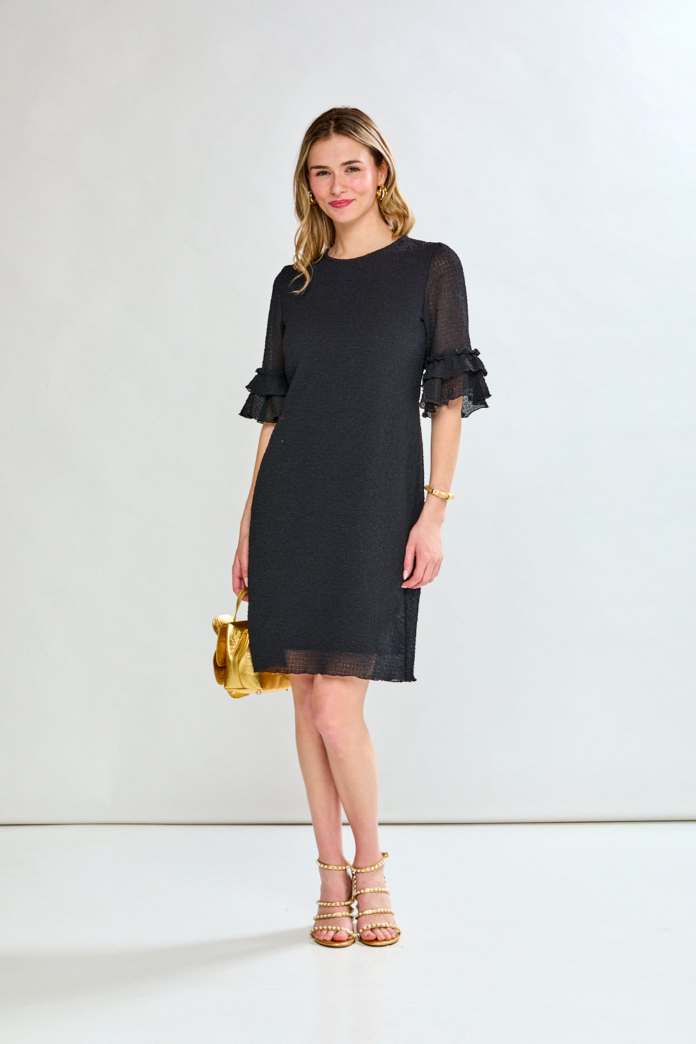 Woman wearing a black dress with ruffled sleeves on a white background