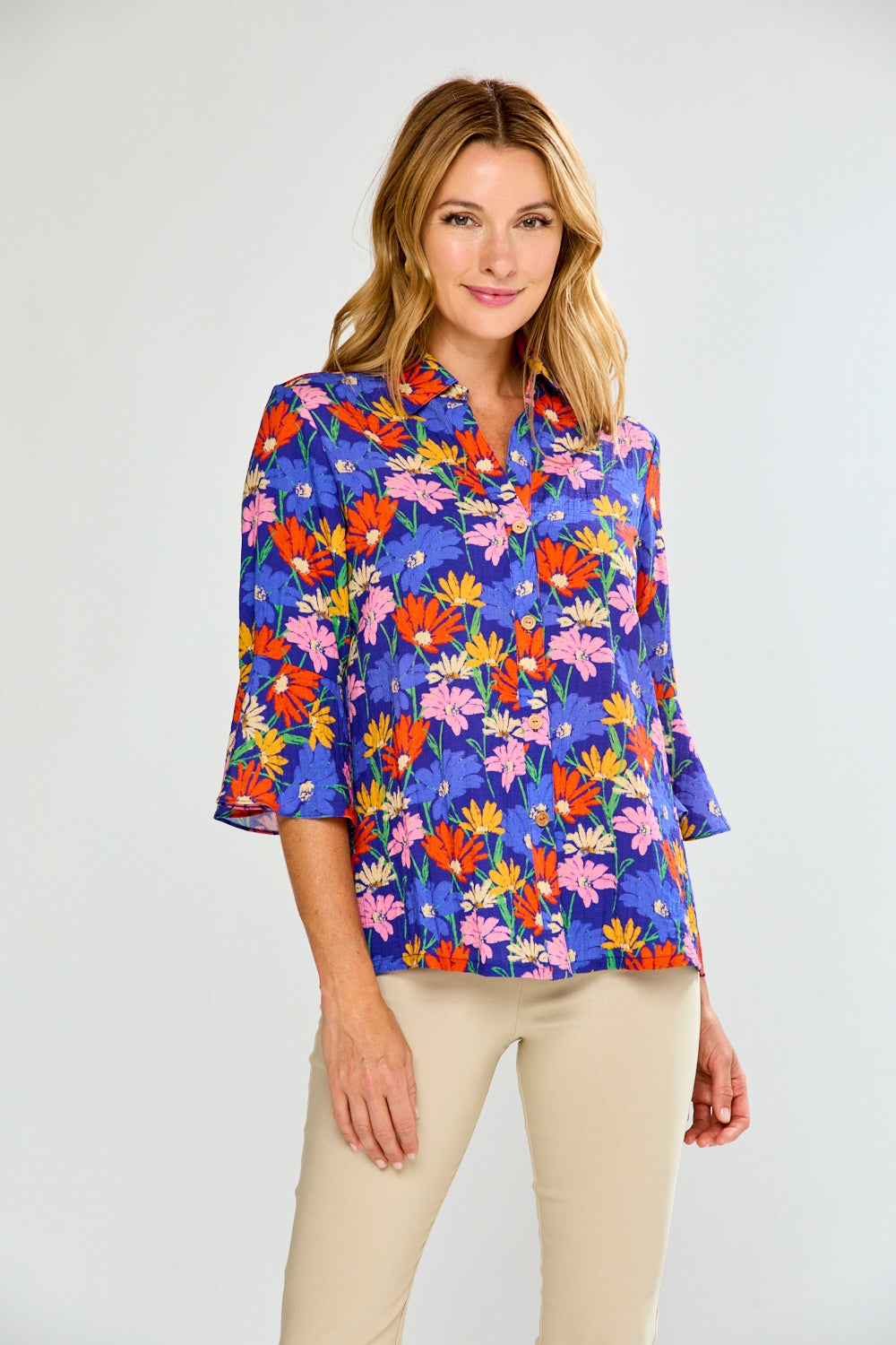 Woman wearing a colorful floral blouse against a white background