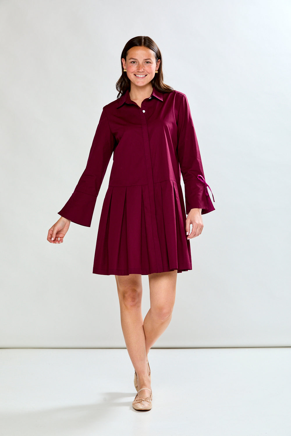 Woman wearing a raisin dress with long sleeves on a white background