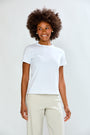 Woman wearing a white t-shirt and beige pants against a plain background