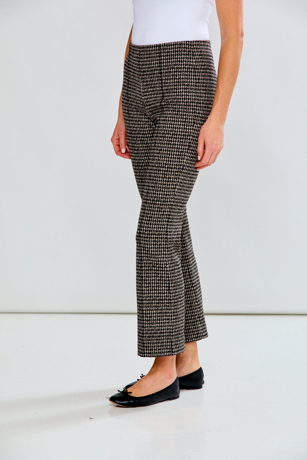 Person wearing houndstooth patterned pants on a plain background