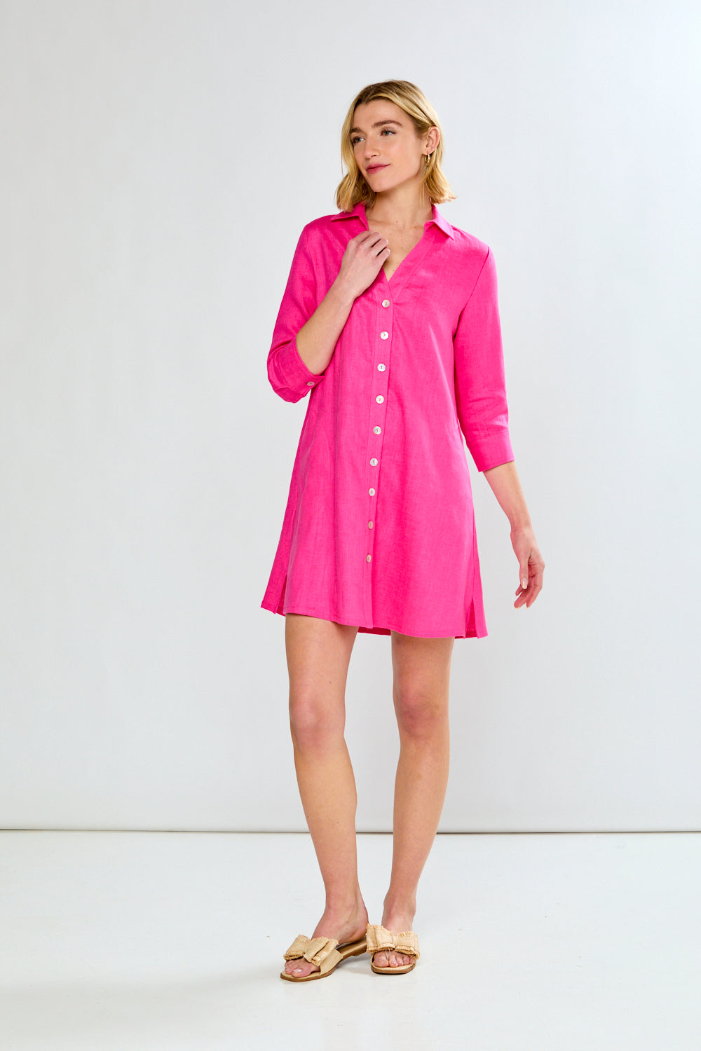 Woman wearing a pink shirt dress against a white background