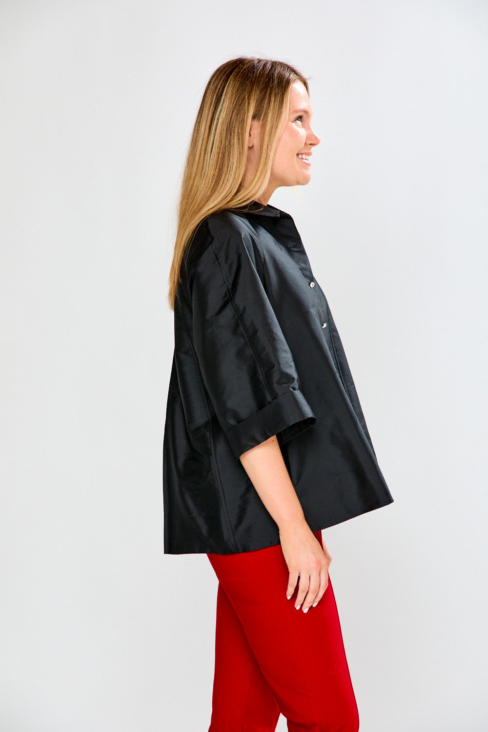 Woman wearing a black jacket and red pants on a white background