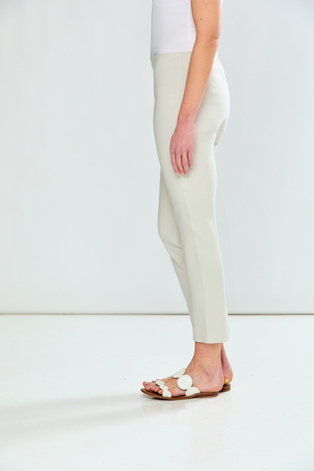 Person wearing white pants and sandals on a plain background