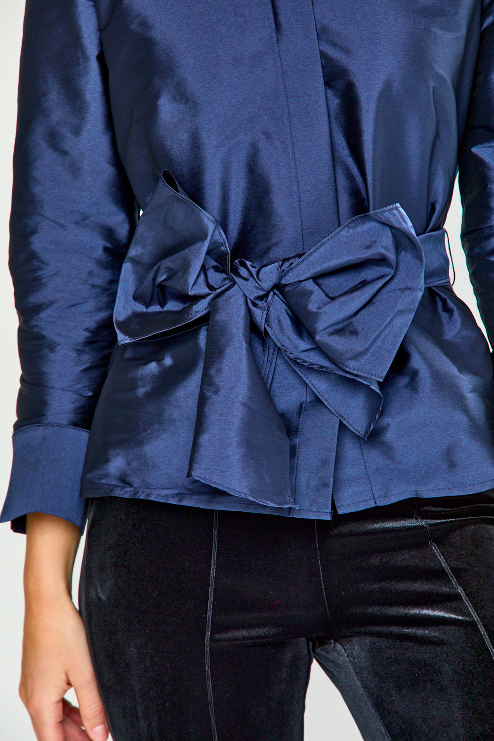 Woman wearing a blue blouse with a bow detail on a white background