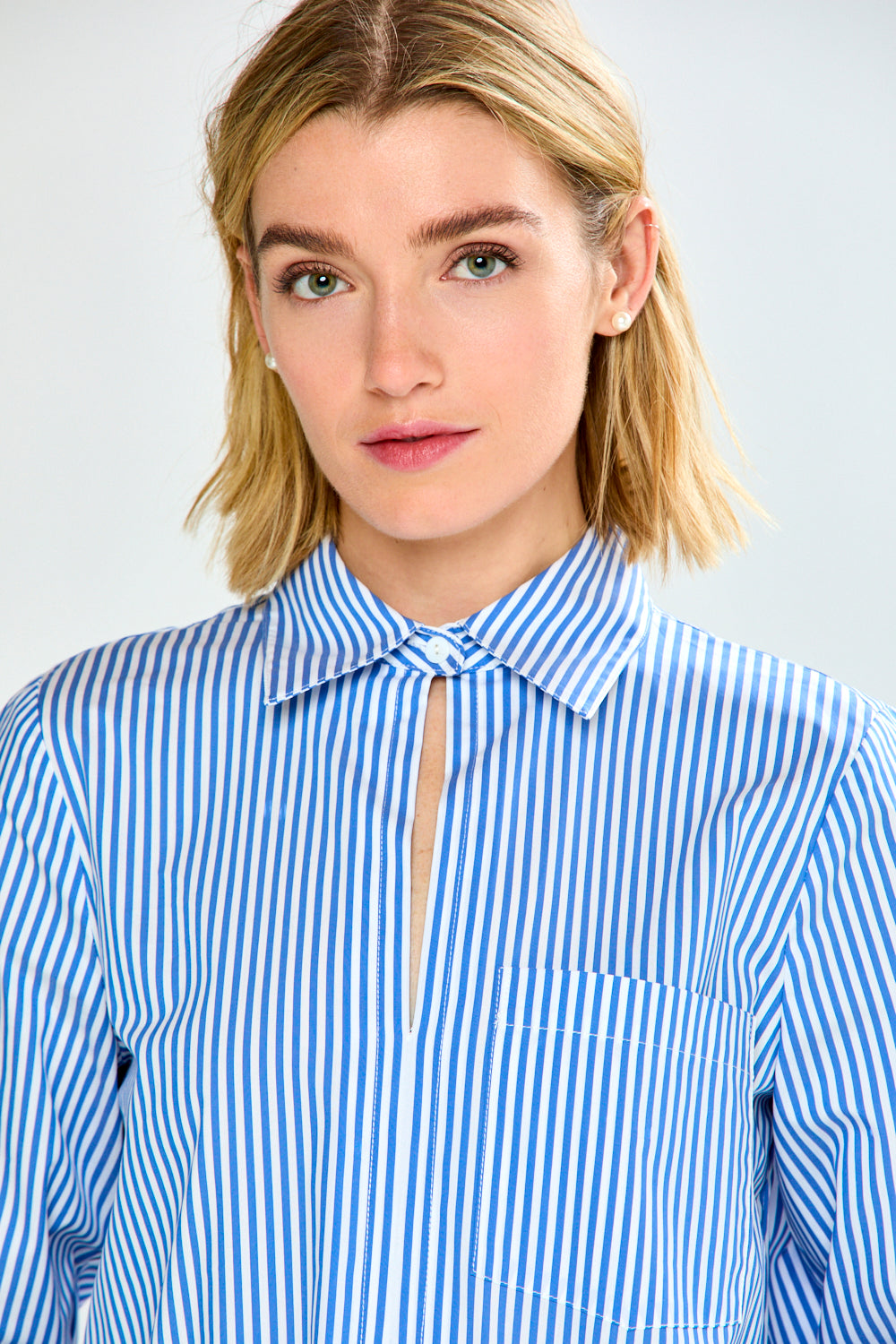 Person wearing a blue and white striped shirt against a plain background