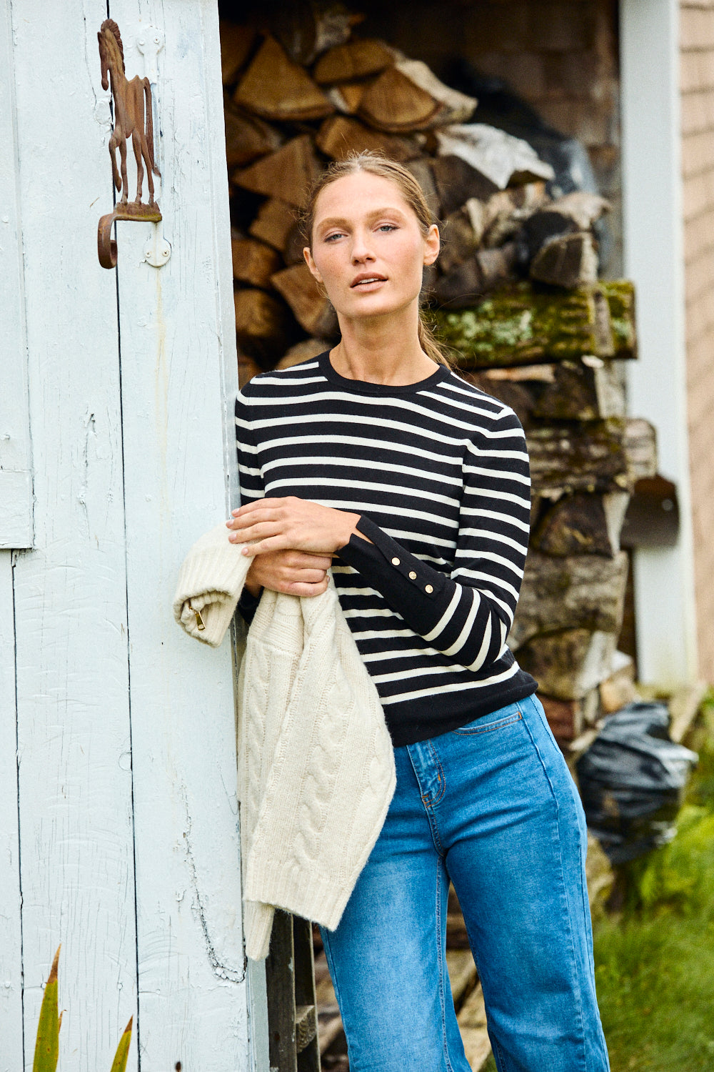 Woman wearing a black and white striped sweater and blue jeans