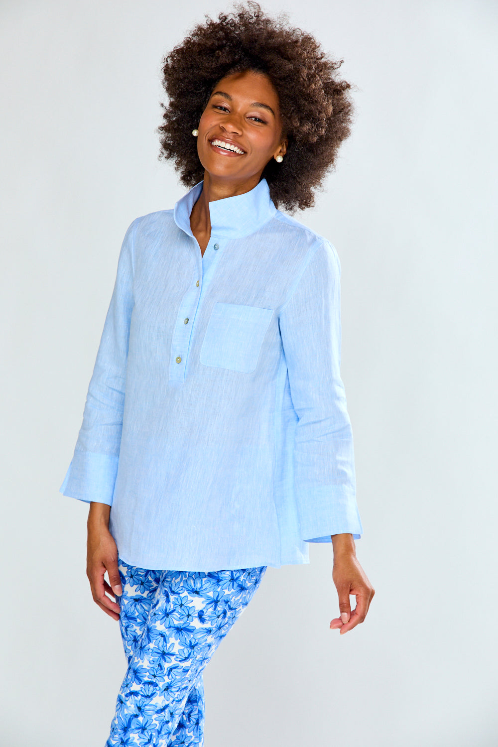Woman wearing a light blue shirt and floral pants on a white background