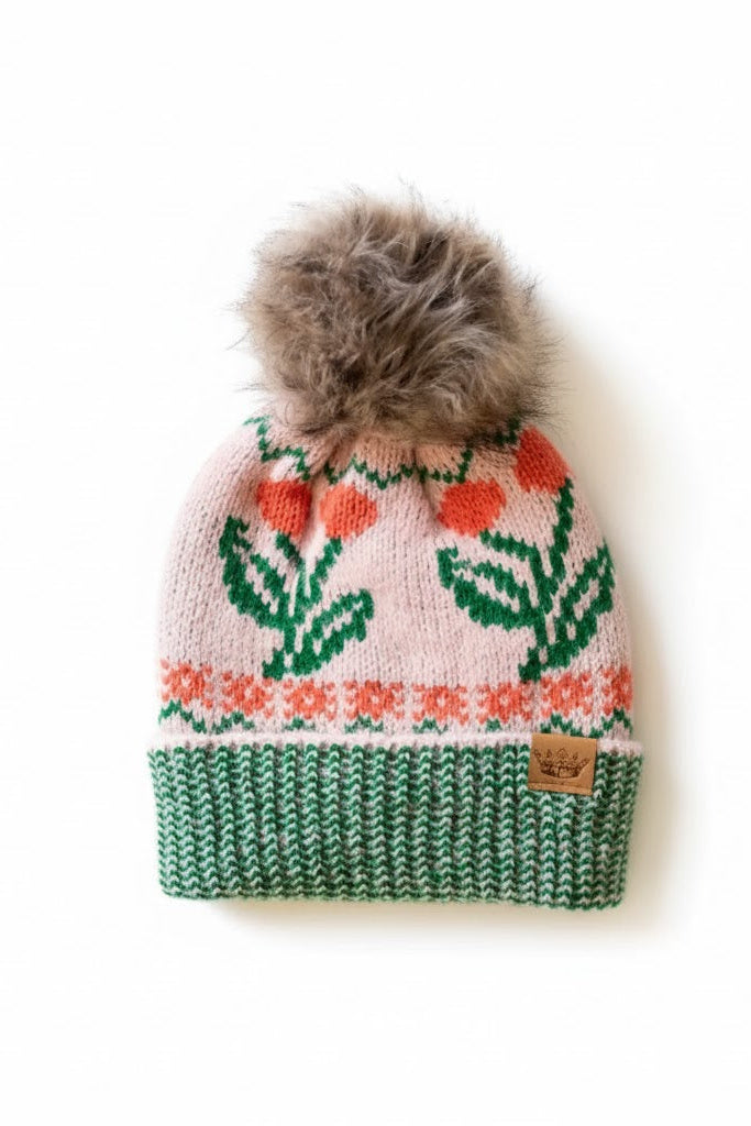 Knitted beanie with floral pattern and fur pom-pom on a white background