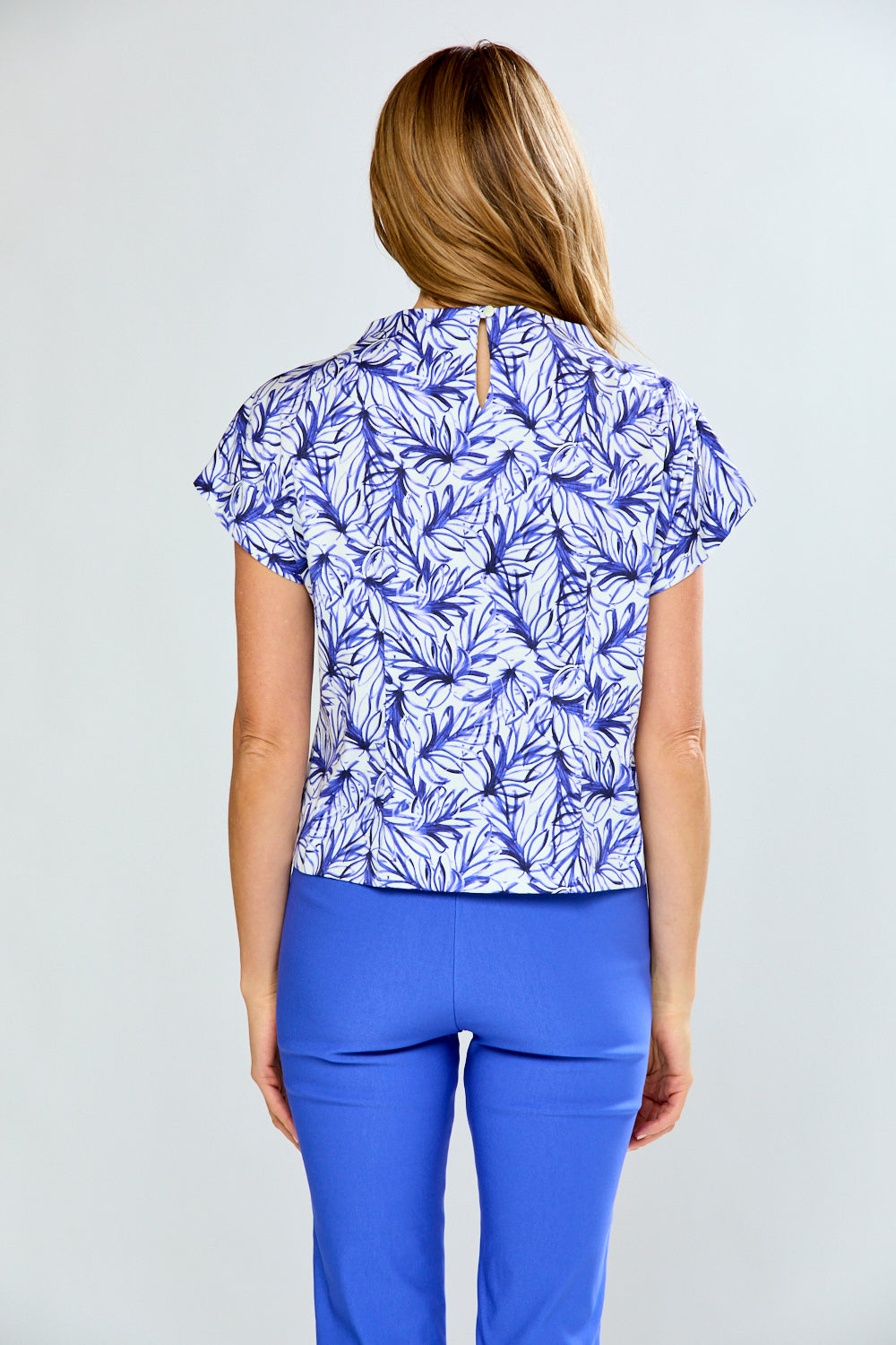 Woman wearing a blue and white patterned top with matching pants on a light gray background