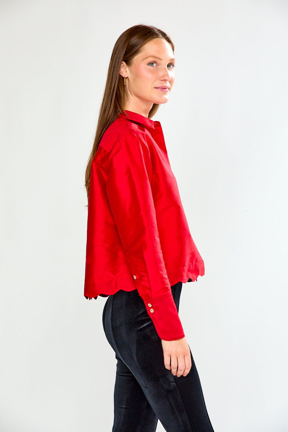 Woman wearing a red shirt and black pants on a white background
