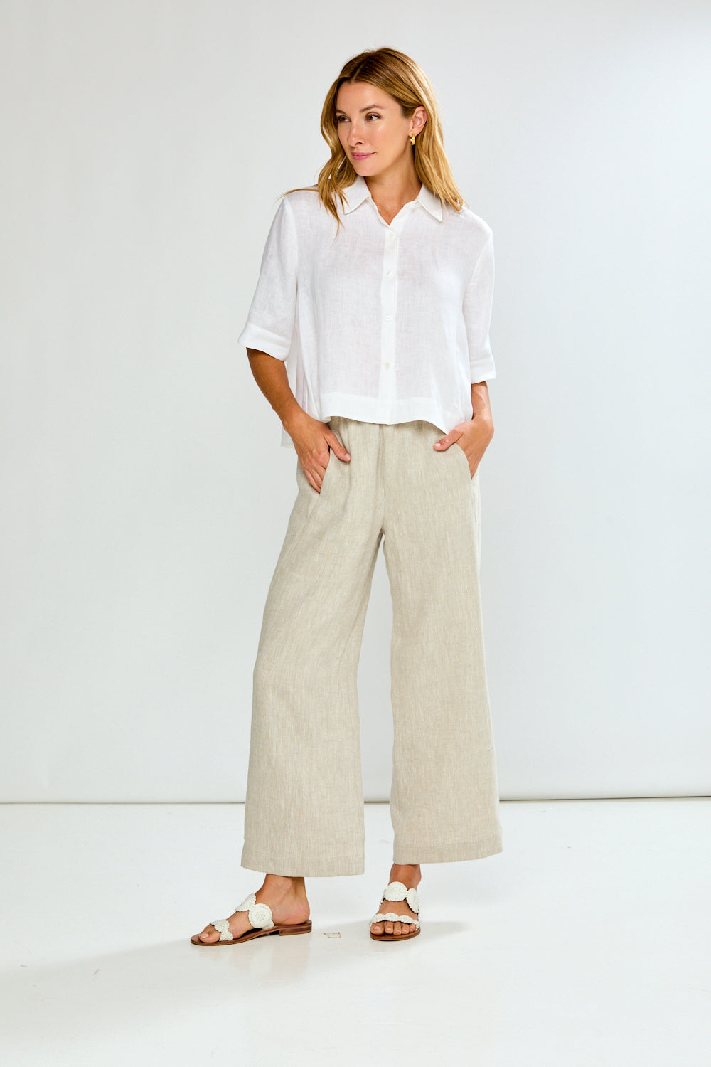 Woman wearing a white shirt and beige pants against a white background