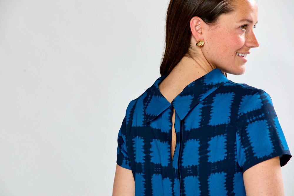 Woman wearing a blue checkered dress against a white background