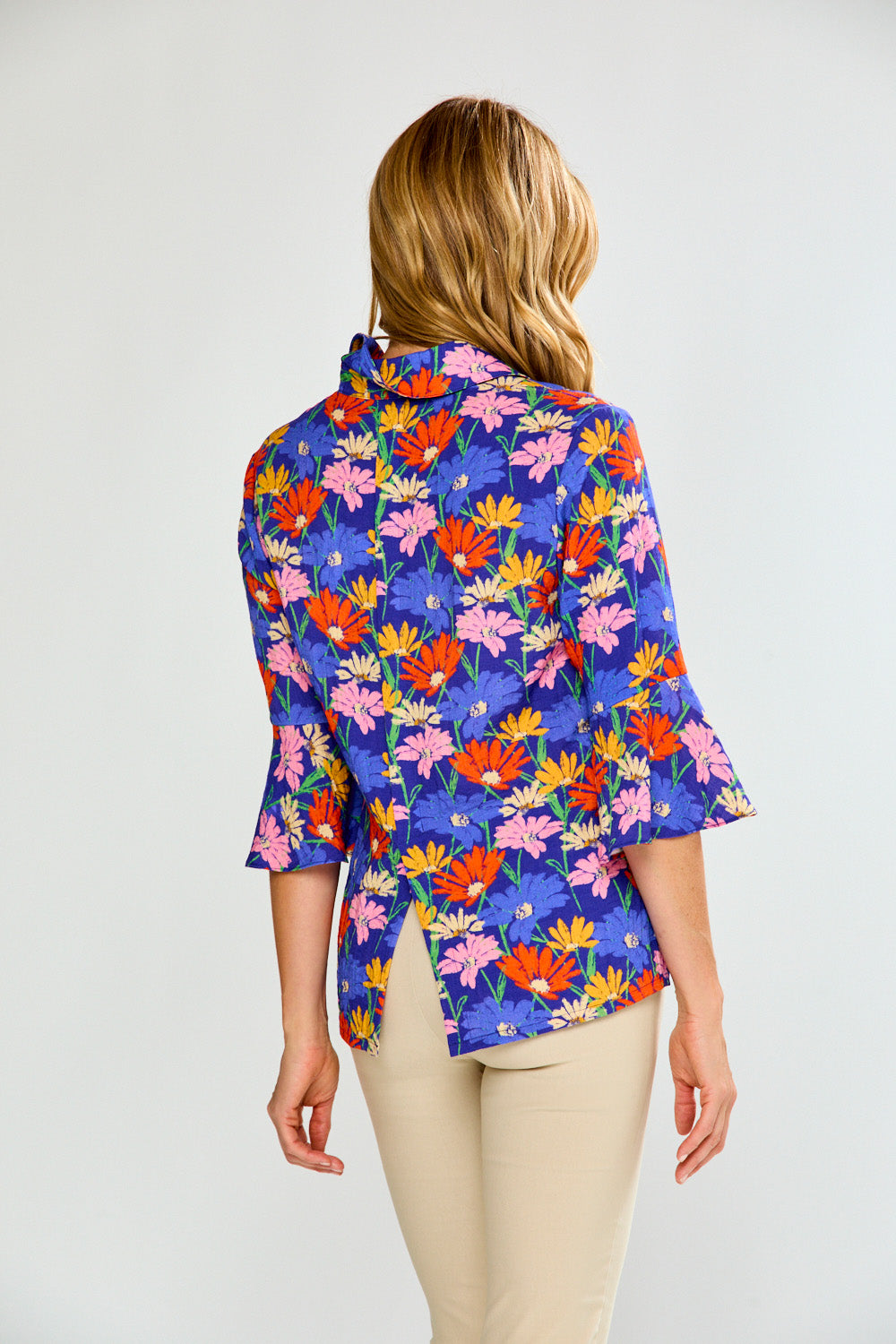 Woman wearing a colorful floral blouse on a plain background