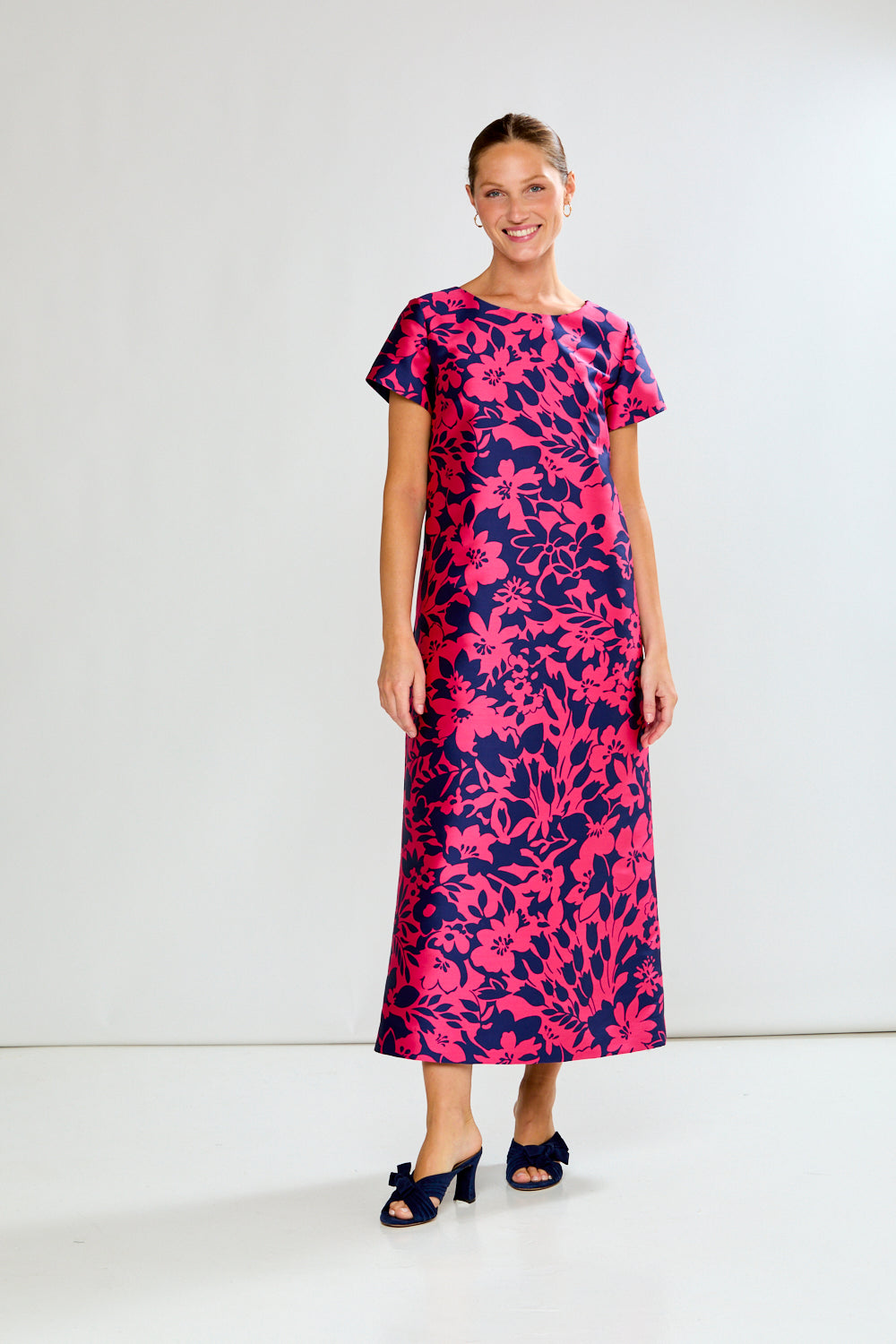 Woman wearing a pink and purple floral dress on a white background