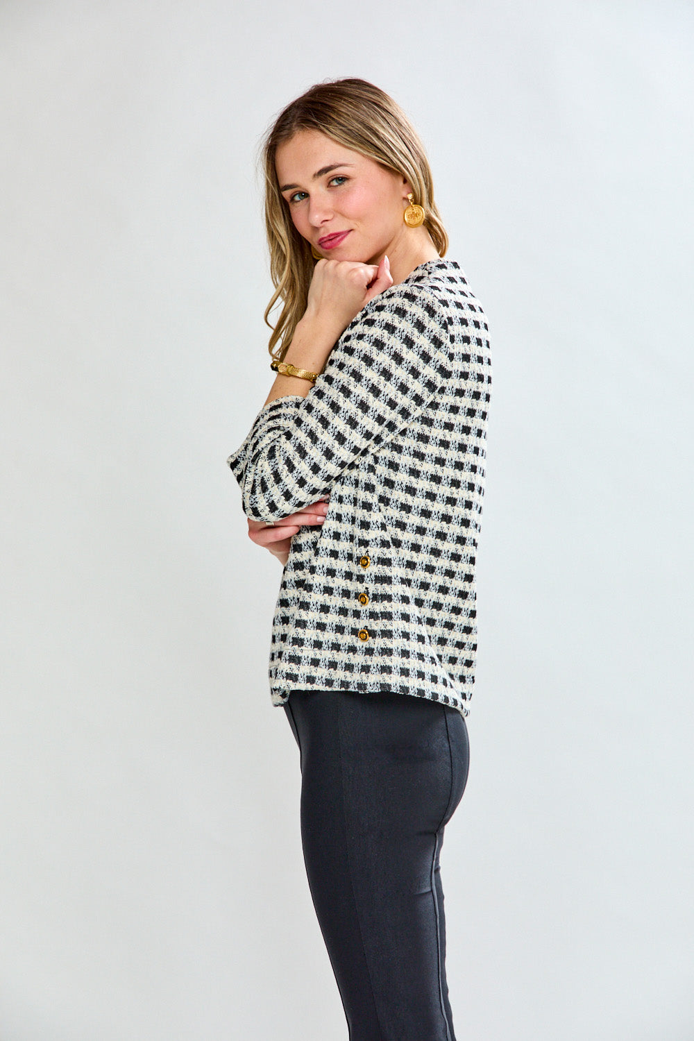 Woman wearing a black and white checkered blouse against a plain background