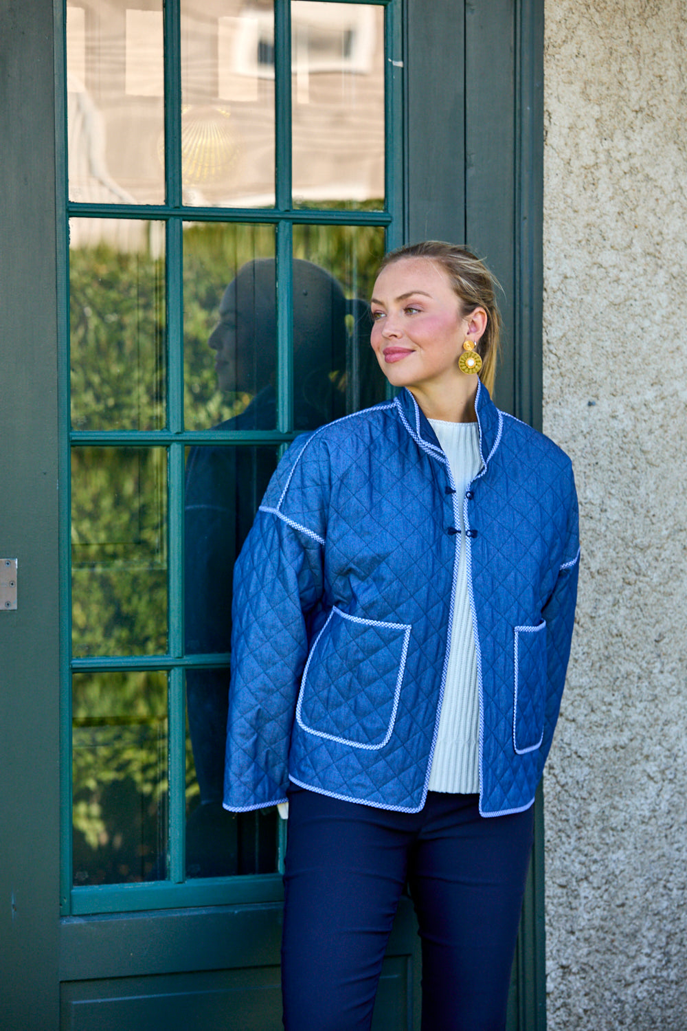 Woman wearing a blue quilted jacket standing outside a building.