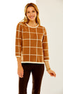 Woman in camel/ivory windowpane sweater