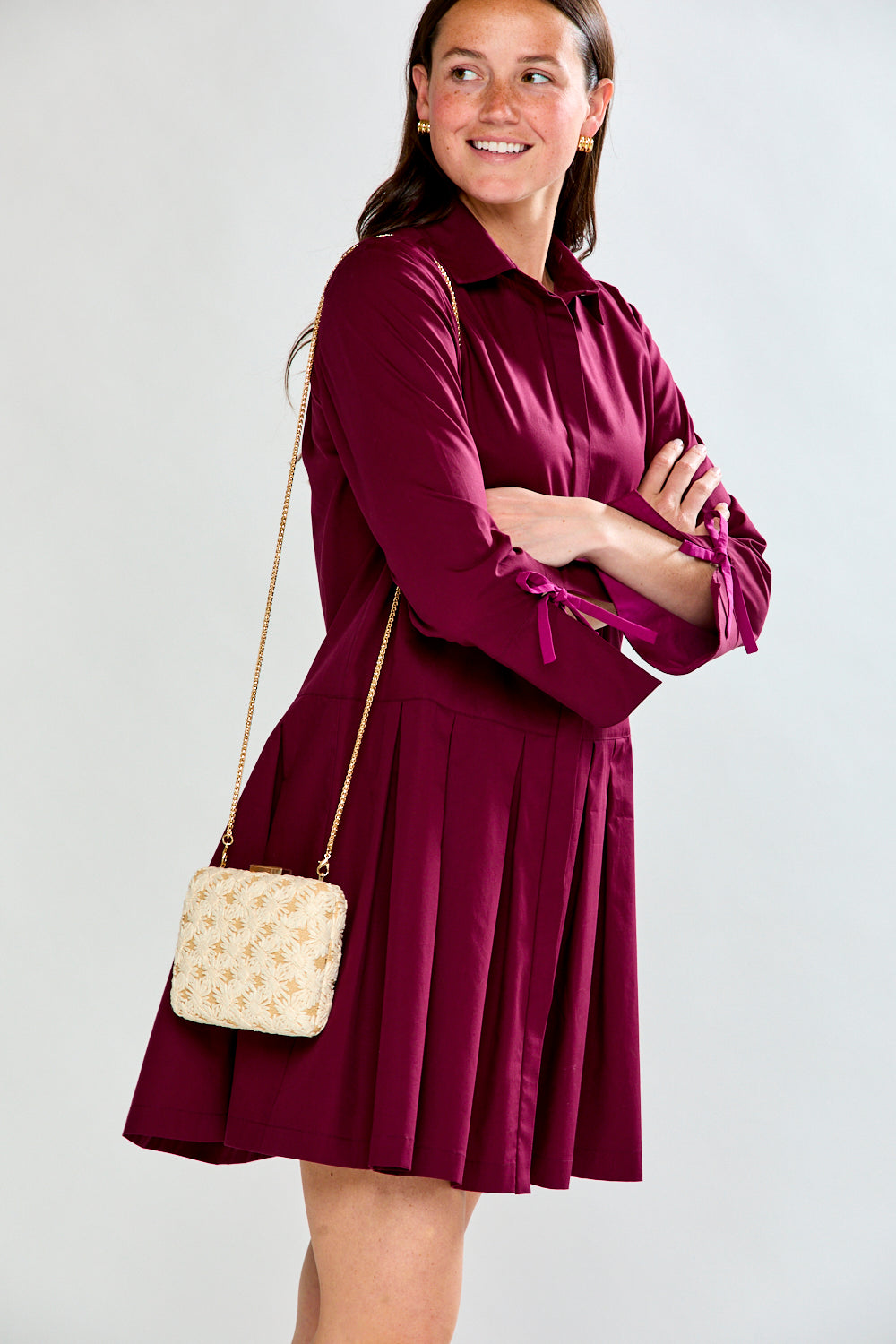 Woman wearing a raisin dress with long sleeves on a white background