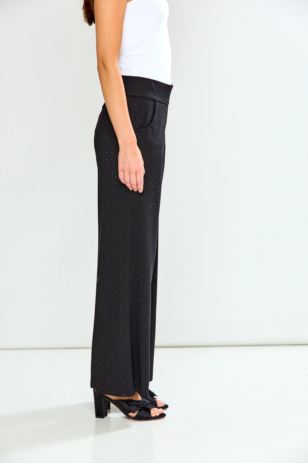 Person wearing black pants with a subtle pattern on a white background