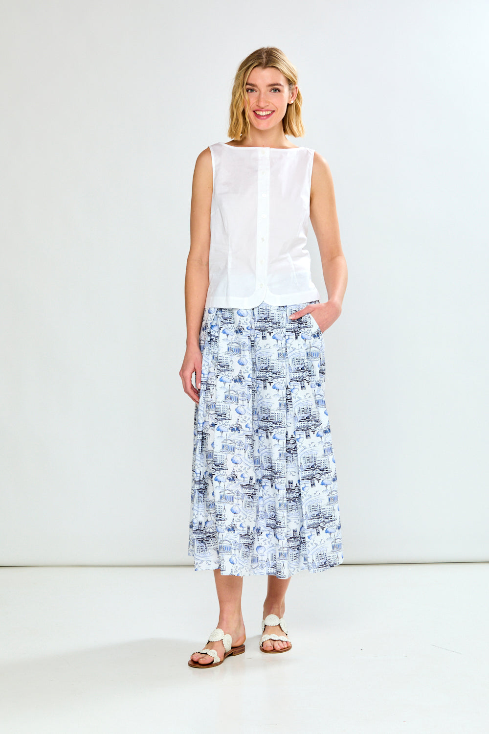 Woman wearing a white sleeveless top and a patterned skirt on a white background