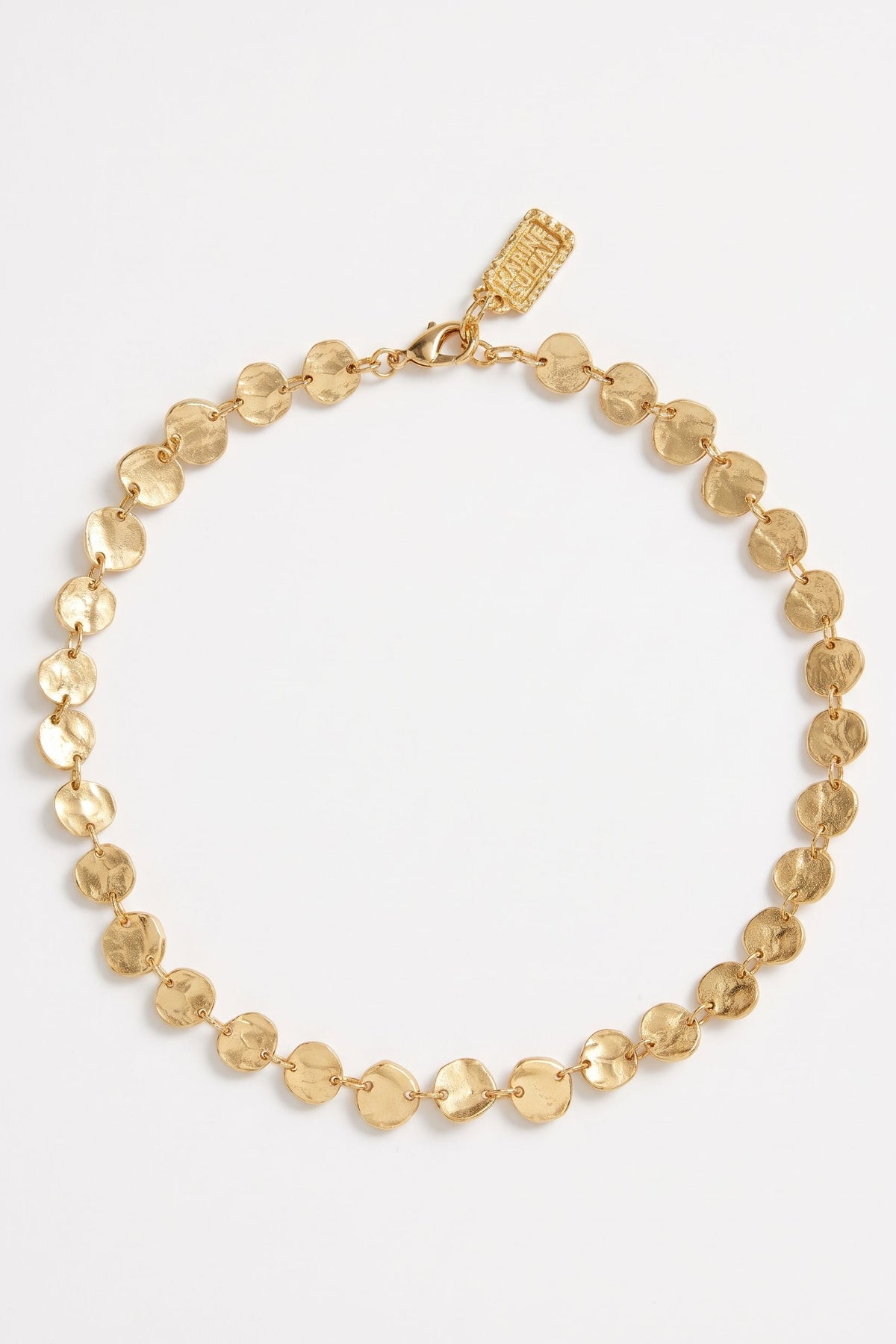 A gold chain necklace featuring textured, disc-like links, displayed on a clean white background with a small brand tag attached at the clasp.