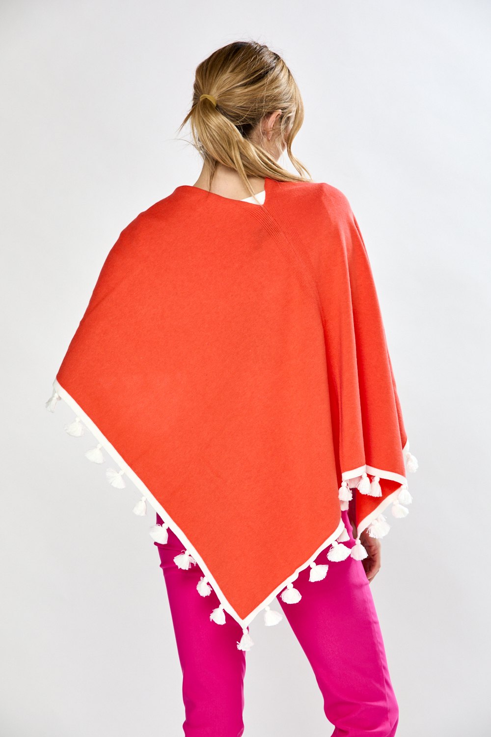 Woman in coral/white tassel ruana