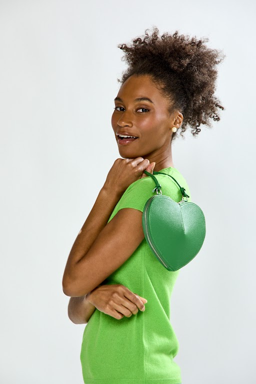 Woman holding a green heart-shaped bag against a white background