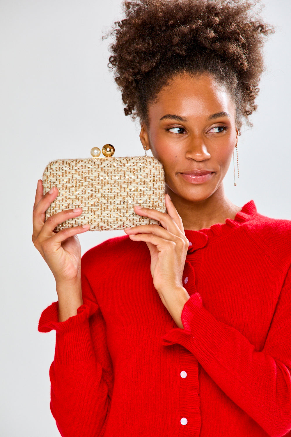 Woman holding a gold clutch against a white background