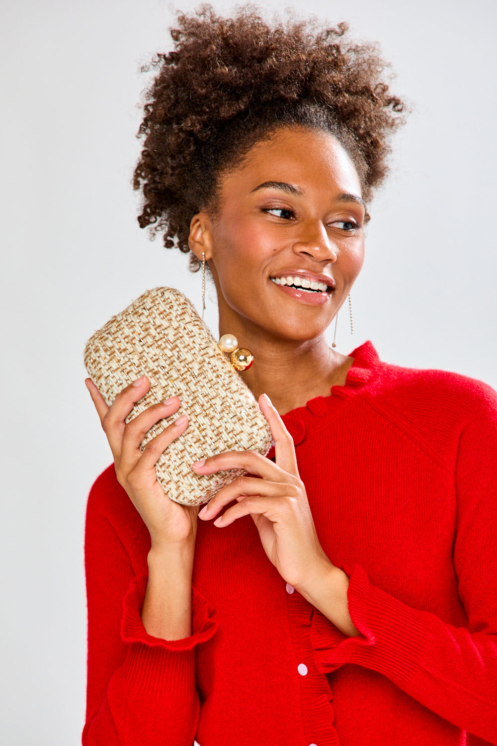 Woman holding a gold clutch against a white background