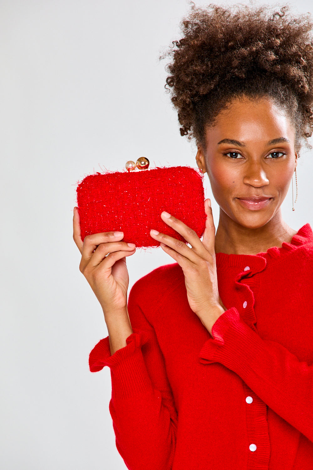 Woman holding a red clutch against a white background