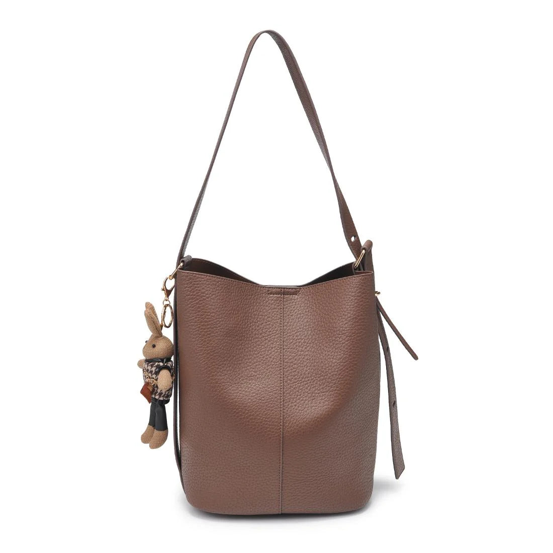 Brown leather handbag with a strap and a small rabbit-shaped keychain on a white background