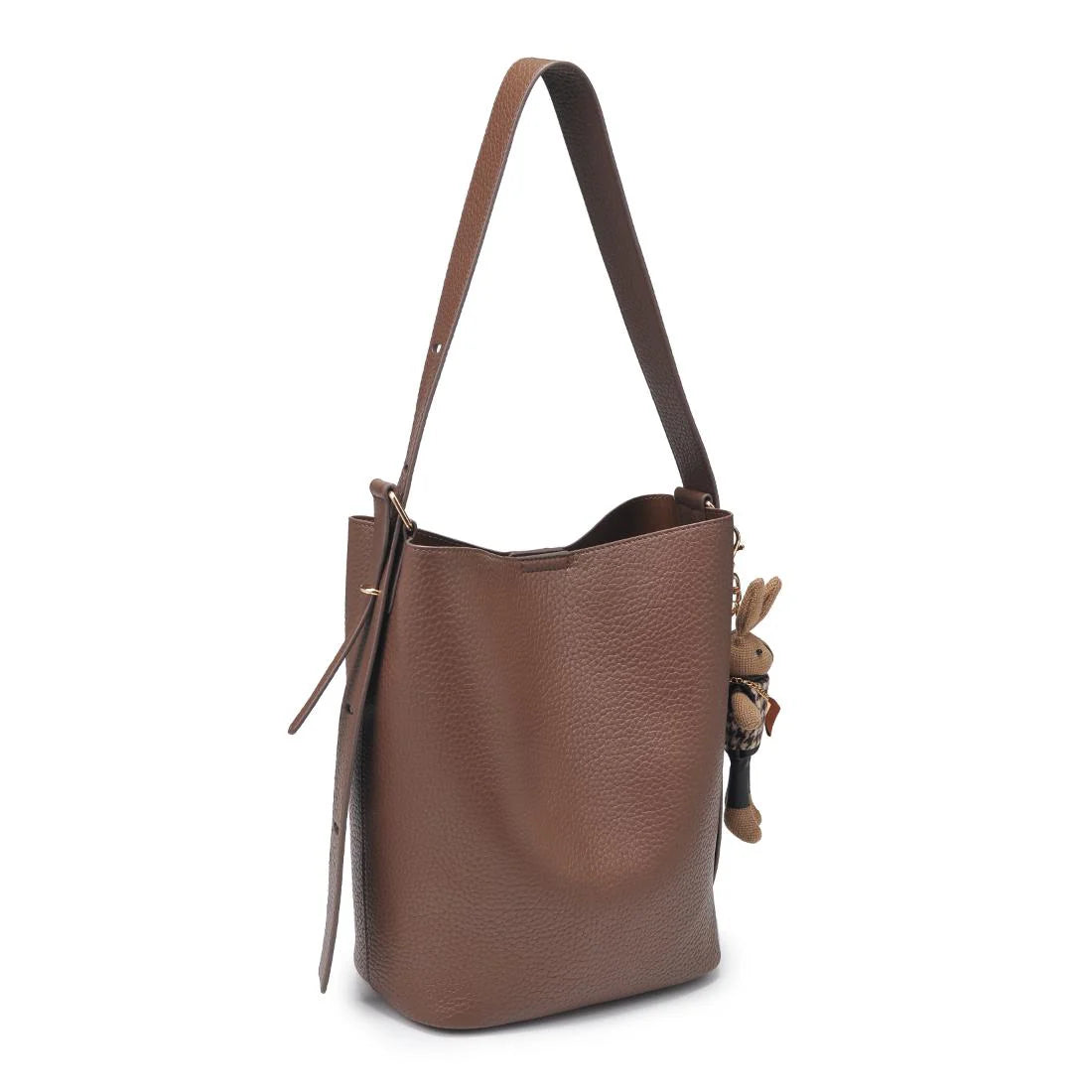 Brown leather handbag with a strap and small rabbit charm on a white background
