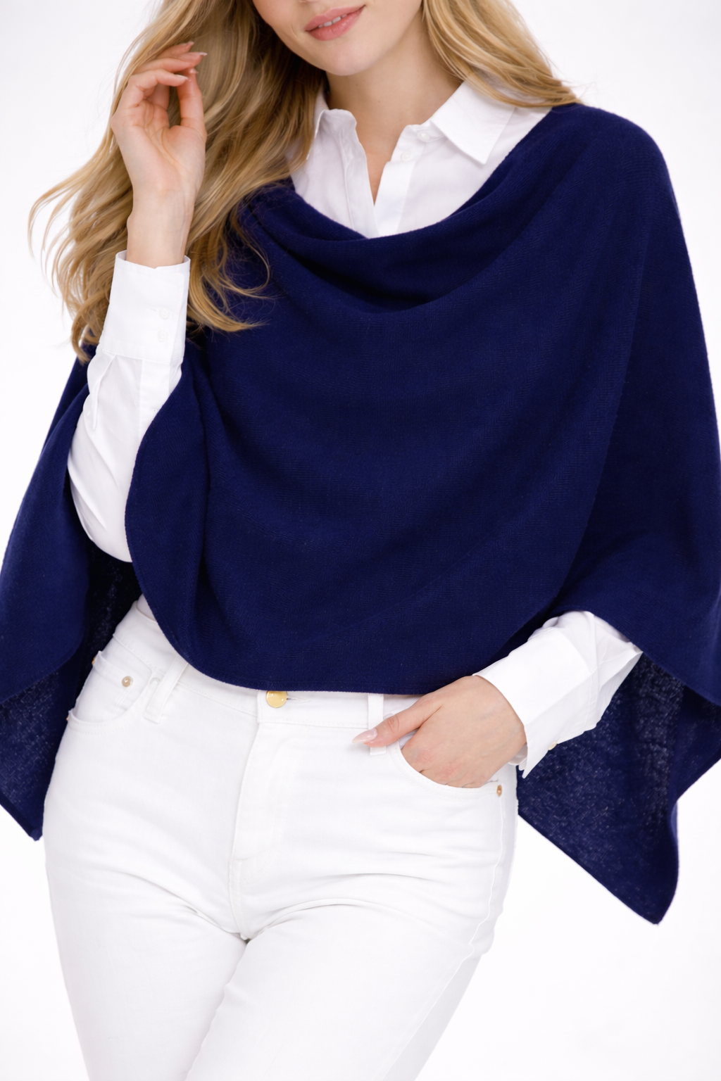 Woman wearing a navy blue poncho over a white shirt and pants on a white background