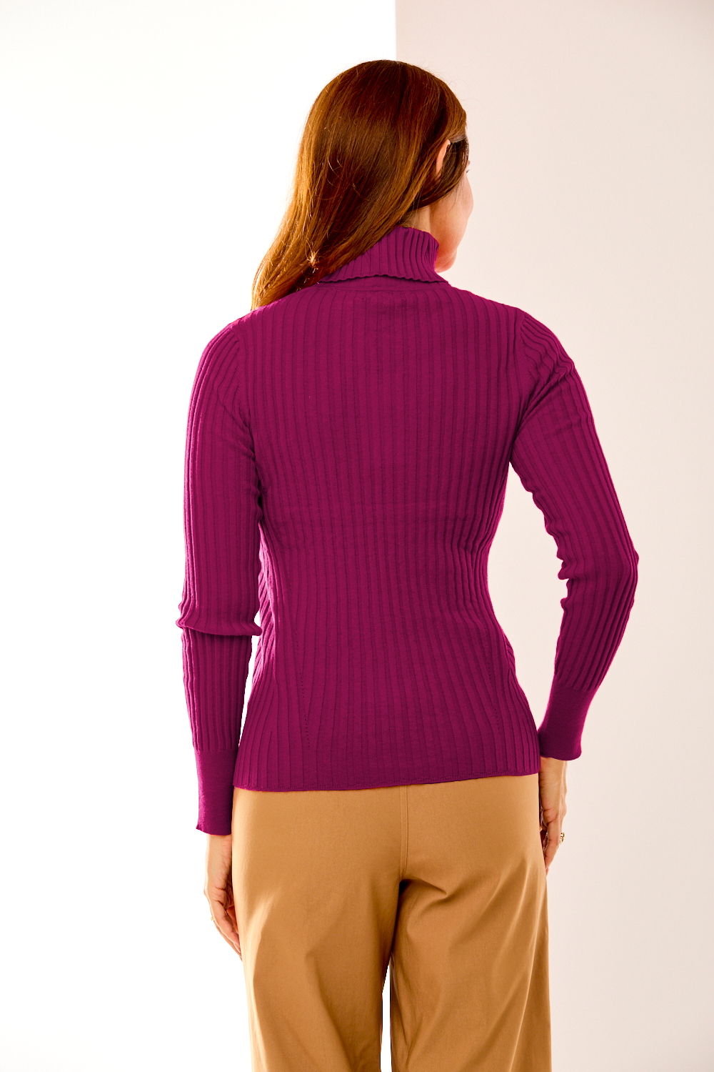 Person wearing a purple ribbed sweater and beige pants against a white background