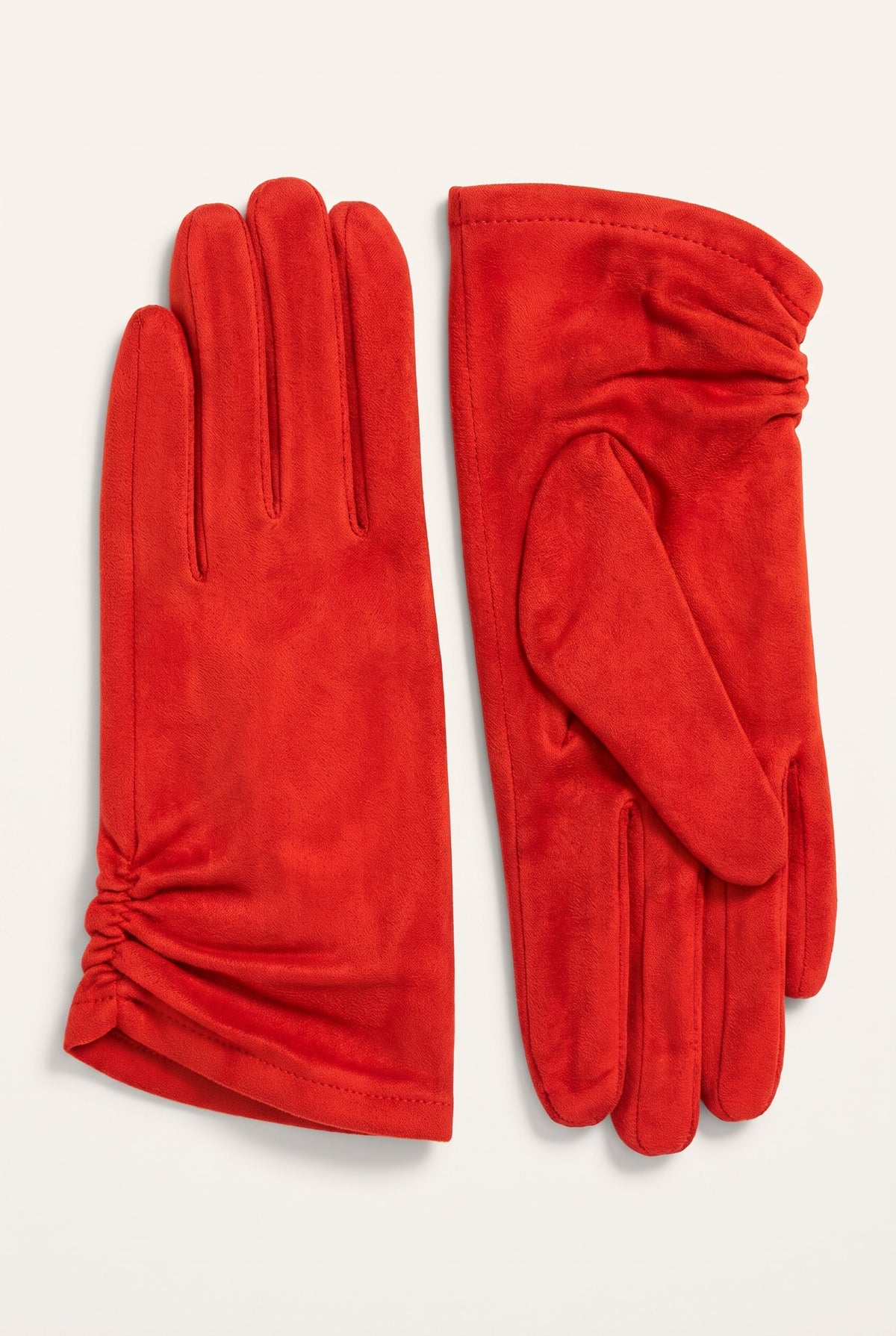 A pair of bright red suede gloves, one showing the back of the hand and the other showing the palm side, laid flat on a light cream background.