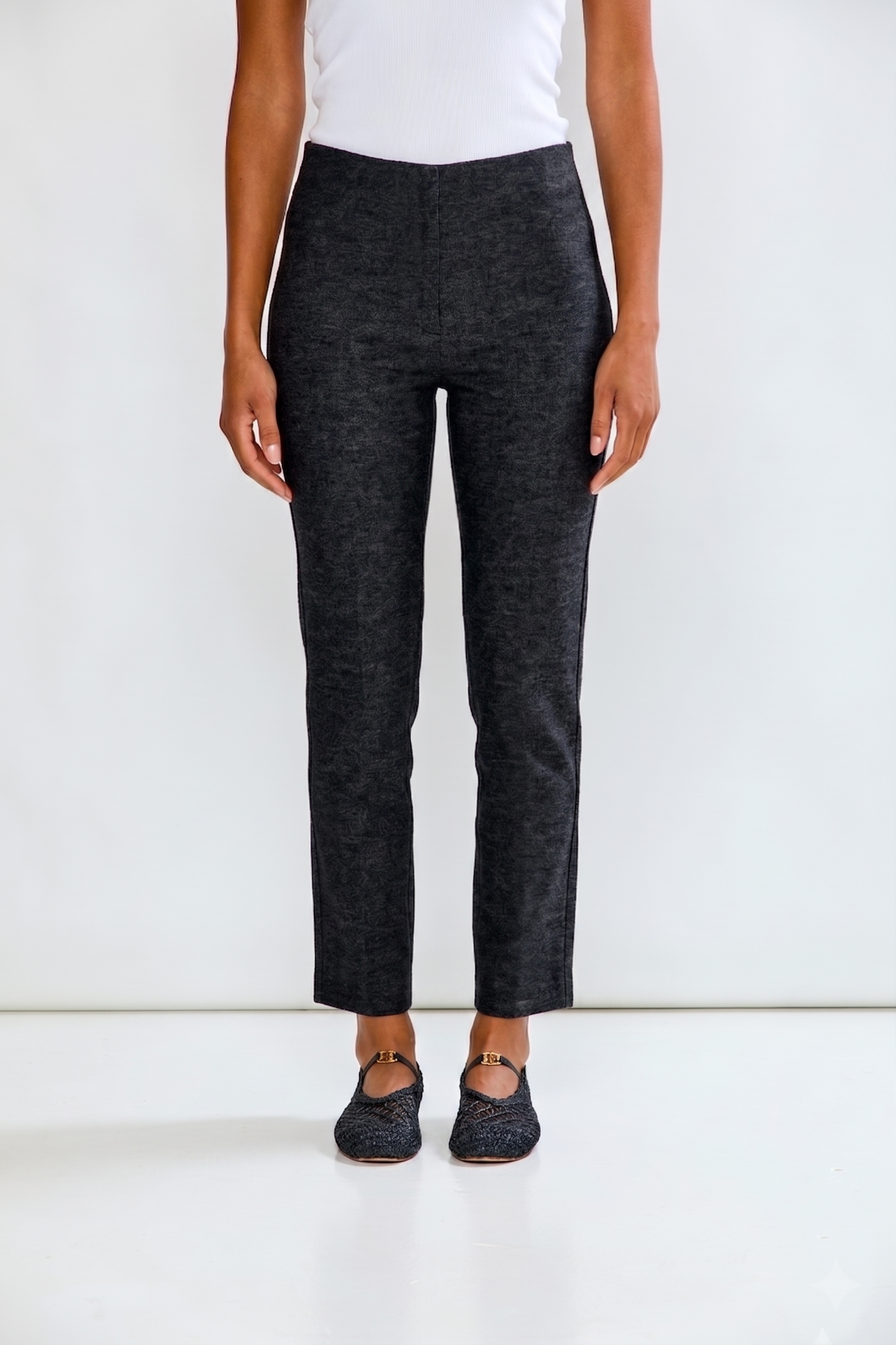 Person wearing dark gray pants and a white top on a white background